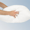 A closeup image of the Down and Feather pillow being squeezed by two hands to show its dense filling.