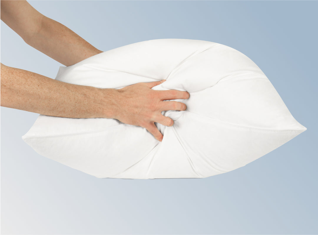 A closeup image of the Down and Feather pillow being squeezed by two hands to show its dense filling.