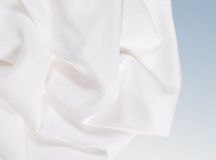 A closeup of the Tencel Sheet Set on a blue background